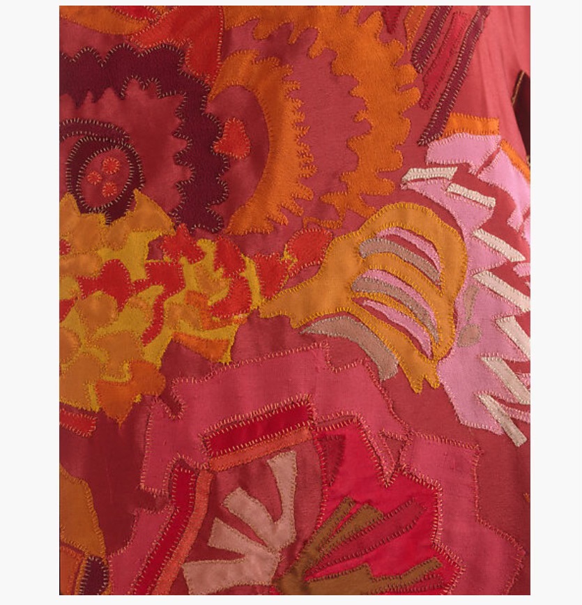 Close up of fabric with abstract pattern in red, orange and pink.