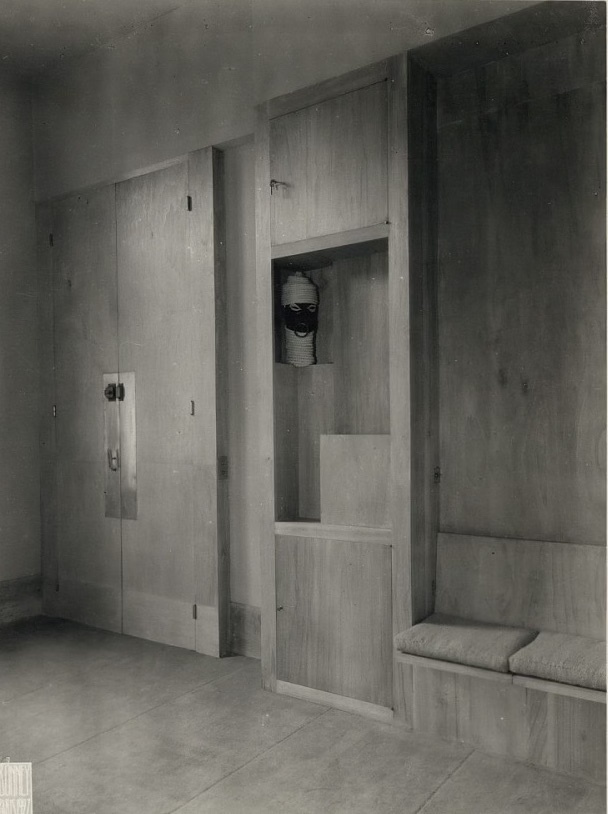 Boutique interior late 1920s. Black- and white photo. Shelf and wallmounted seating area.